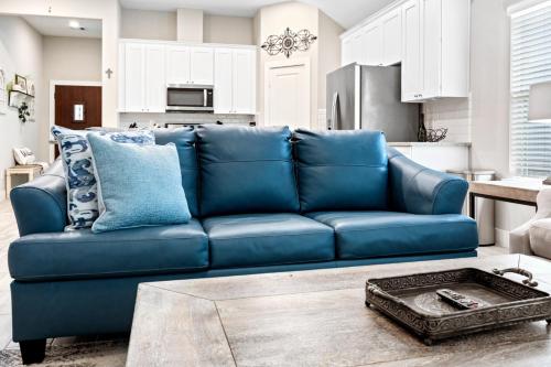 a blue couch in a living room with a kitchen at Conroe 3BR Sleeps 12 | Fenced Yard + Garage Games in Conroe