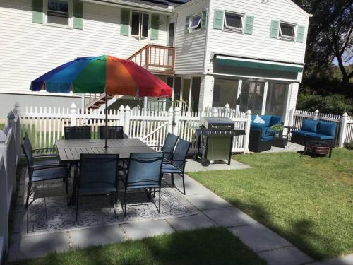 a table with a colorful umbrella in a yard at 597) Sleeps 12 - Pool - Grill in Wolcott