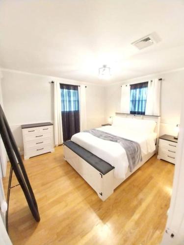 a white bedroom with a large bed and wooden floors at 597) Sleeps 12 - Pool - Grill in Wolcott