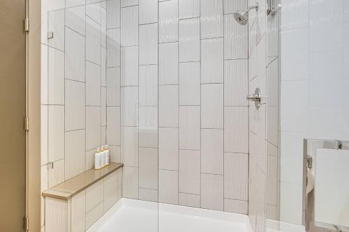 a bathroom with a shower with white tiled walls at Modern Oasis-lots Of Amenities Including A Pool! 