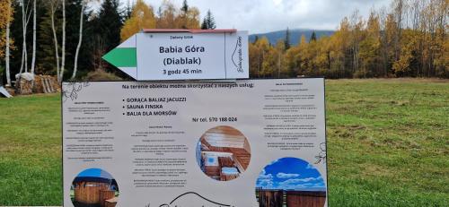 a sign in the middle of a field at Babiogórskie Domki in Lipnica Wielka