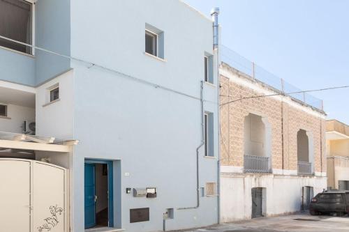 Una fachada de un edificio blanco con una puerta azul. en Dimora Mini Coccola - Salento Reservation, en Ugento