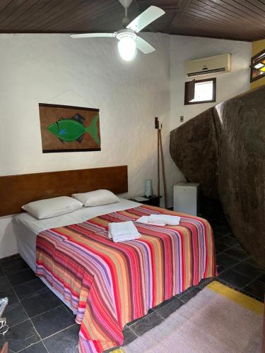 a bedroom with a bed with a colorful blanket at Pousada Cachoeira in Abraão