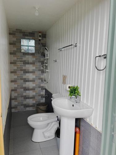 a bathroom with a white toilet and a sink at Casa de Descanso in Kiawagan