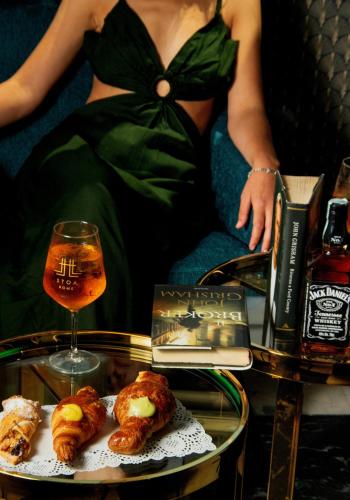 a woman in a green dress sitting next to a table with a drink at STOA ROME Boutique Suites in Rome