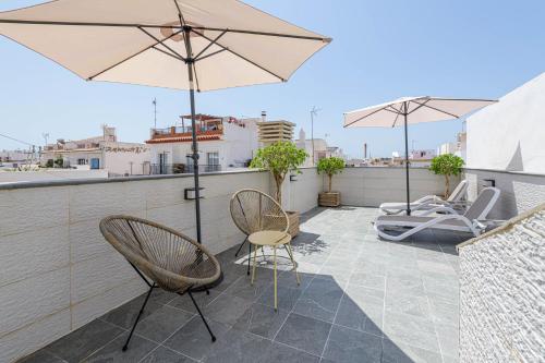 a patio with two chairs and an umbrella on a roof at Nueva 22 Suites in Nerja by Solaga Holiday Homes in Nerja