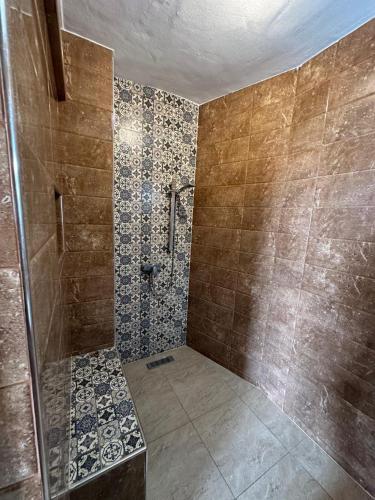 a bathroom with a shower and a tiled wall at Appartement à usage familial in Agadir