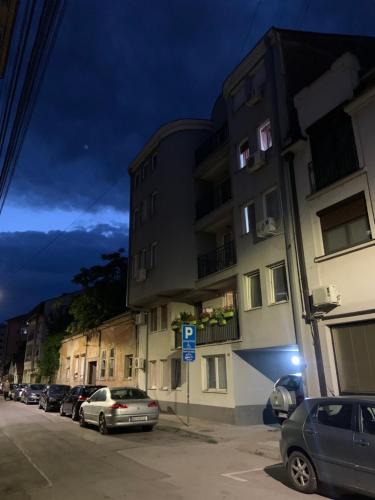 a street with cars parked in front of a building at Urban Hideout City Center Nis in Niš