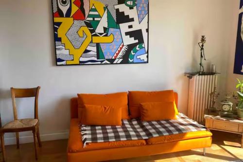 un canapé orange dans une pièce avec un tableau sur le mur dans l'établissement Beautiful T2 with balcony near downtown, à Nice