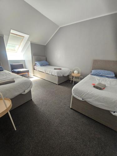 a room with three beds and a table and chairs at Cunninghame 4 in Beith