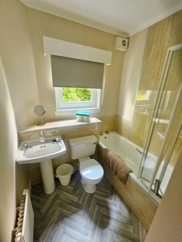 a bathroom with a toilet and a sink and a tub at Cunninghame 4 in Beith