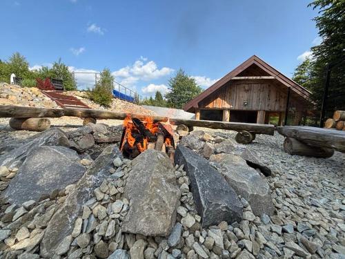 a fire pit with rocks and a log at Pensjonat pod Samowarem in Tylicz