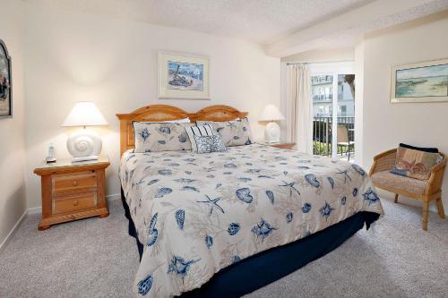 a bedroom with a bed and a chair and a window at Beach Club #118 in Saint Simons Island