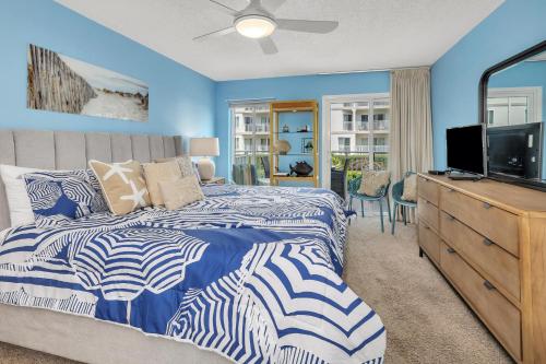 a bedroom with blue walls and a bed with a television at Beach Club #127 in Saint Simons Island