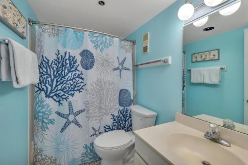 a bathroom with a shower curtain with a toilet and a sink at Beach Club #127 in Saint Simons Island