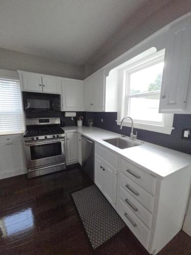 a kitchen with white cabinets and a sink and a stove at The Fairview in Peabody