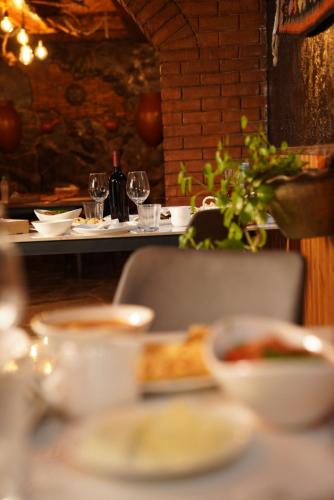 a table with a plate of food and wine glasses at Hotel Hobbiton near Vardzia Caves in T'mogvi
