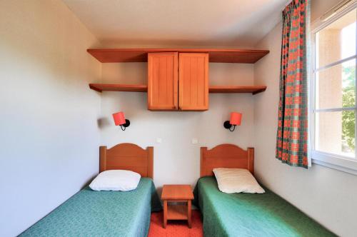 deux lits jumeaux dans une chambre avec fenêtre dans l'établissement La résidence du Lac - maeva Home - Appartement 2 pièces 4 personnes - Sélection MAE-7331, à Monflanquin