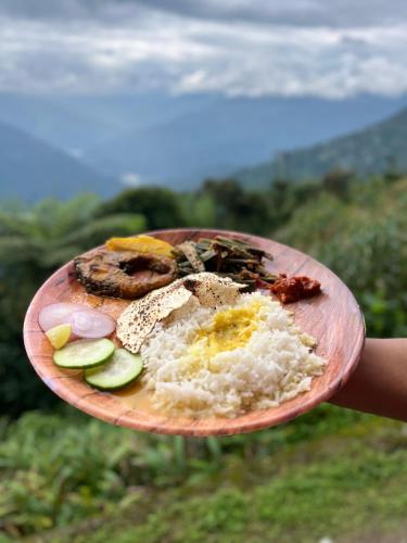 a person holding a plate of food with rice and vegetables at Homestay Ramdhura Heights in Pedong