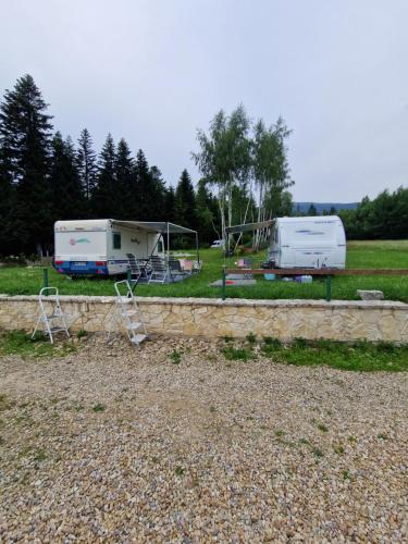 two rvs parked in a field with trees at Babiogórskie Domki in Lipnica Wielka