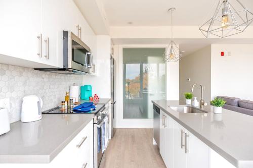 a kitchen with white cabinets and a sink at Contemporary 3BR with Natural Light High Park North Nearest Intersection - Dorval Rd, in Toronto