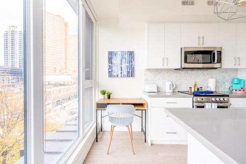 a kitchen with white cabinets and a large window at Contemporary 3BR with Natural Light High Park North Nearest Intersection - Dorval Rd, in Toronto
