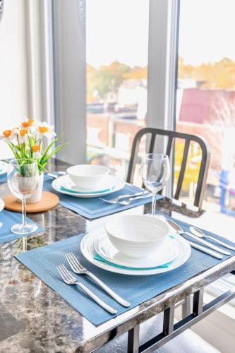 a table with plates and silverware on top of a table at Contemporary 3BR with Natural Light High Park North Nearest Intersection - Dorval Rd, in Toronto