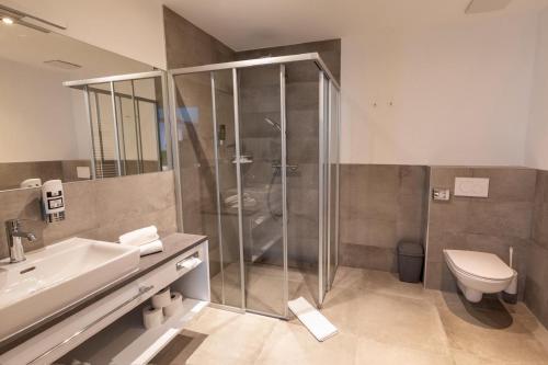 a bathroom with a shower and a sink and a toilet at Hotel Ertl & Restaurant EL Venado in Spittal an der Drau