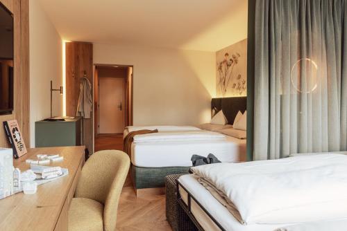 a hotel room with two beds and a desk at Hotel Römerhof Superior in Obertauern