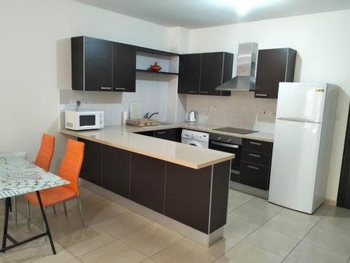 a kitchen with black cabinets and a white refrigerator at Regina by the Sea in Limassol