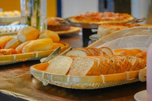 a table with several trays of bread and pizzas at VELINN Pousada Bromelias in Ilhabela