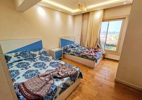 a bedroom with two beds and a large window at فيلا فاخرة أول صف على البحيرة الرملية in El Alamein