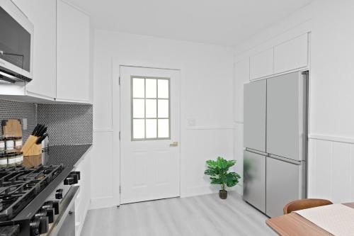 a white kitchen with a door and a plant at 15m to NY Cozy Relaxing Home in Hackensack