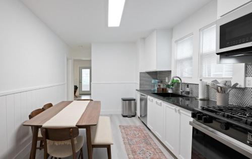 a white kitchen with a wooden table and a counter top at 15m to NY Cozy Relaxing Home in Hackensack