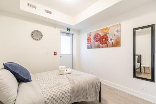 a white bedroom with a bed and a mirror at Stylish 3BR Condo near High Park Trails Nearest Intersection Dundas St W in Toronto