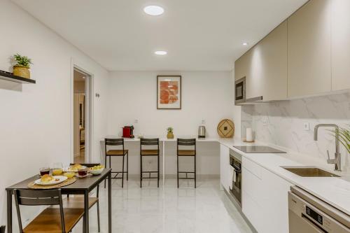 a kitchen with white counters and a table and chairs at Cortes Reais Guesthouse By All2gether in Lisbon