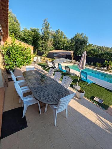 un patio avec une table et des chaises à côté d'une piscine dans l'établissement Maison 4 chambres PISCINE, à Sainte-Anastasie-sur-Issole
