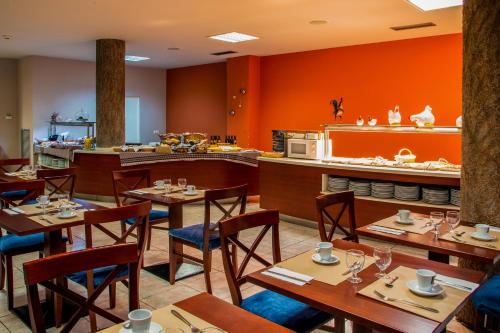 um restaurante com mesas e cadeiras de madeira e paredes cor de laranja em Petit Palau - Adults Only em Blanes