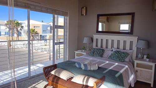 1 dormitorio con cama con espejo y balcón en Beachfront Family Luxury Rental, en Swakopmund