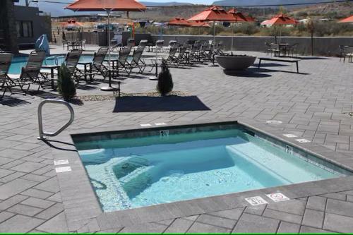 a swimming pool with chairs and umbrellas on a patio at Verde Ranch RV Resort in Camp Verde