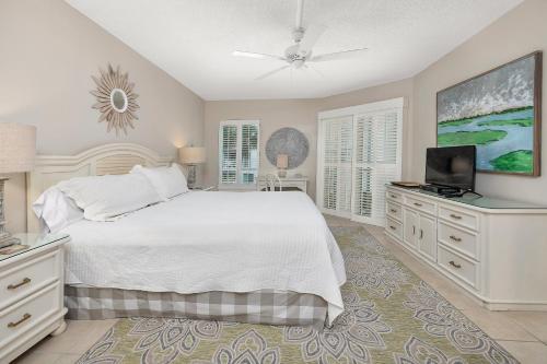 a bedroom with a white bed and a flat screen tv at Beach Club #223 in Saint Simons Island