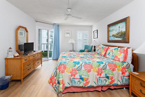 a bedroom with a bed and a dresser with a television at Beach Club #224 in Saint Simons Island