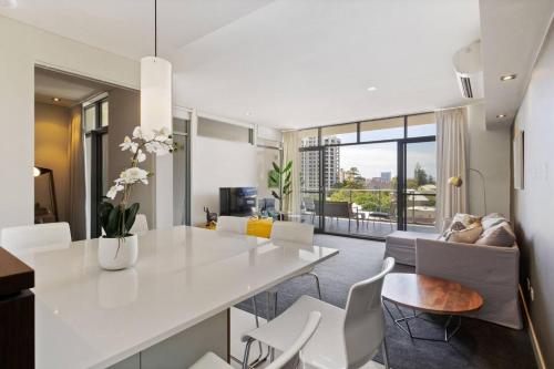 a kitchen and living room with a white table and chairs at SkylineViews 2bdrm River, WACA, Optus stadium in Perth
