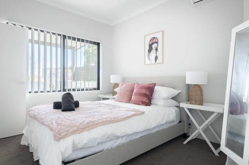 パースにあるChic Exec 2bdr 2bath -river,freo,parking,acのピンクの枕が付いた大きなベッドのある寝室