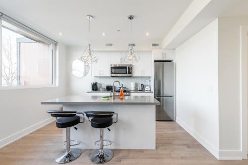 a white kitchen with a counter and two bar stools at Bright & Inviting 3BR Apartment near High Park Nearest Intersection Indian Trail in Toronto