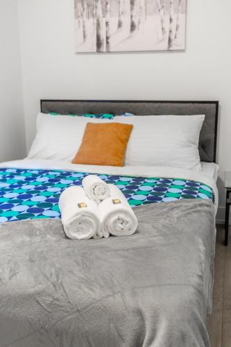 a bed with two towels on top of it at Bright & Inviting 3BR Apartment near High Park Nearest Intersection Indian Trail in Toronto