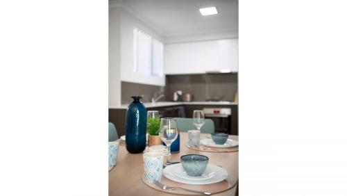 パースにあるBright Trendy 3br Apt - Walk To River & Shopsのグラスと青い花瓶が置かれたテーブルのあるキッチン