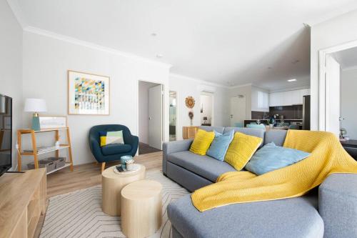 a living room with a blue couch and a yellow blanket at Bright Trendy 3BR Apt - Walk to River & Shops in Perth