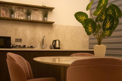 a table with chairs and a plant in a room at Elegant Ephesus Suites - Artemis in Selcuk