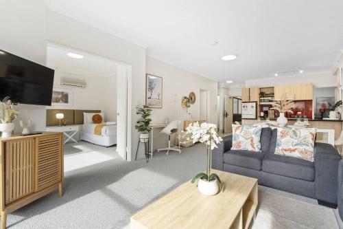 a living room with a blue couch and a bedroom at East Perth Family Zen CATBus, CBD,ElizabethQuay in Perth